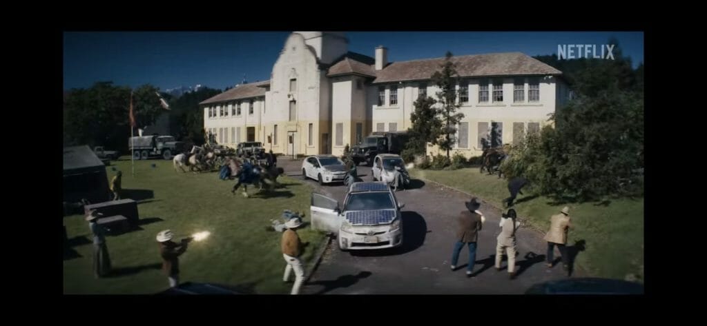 people and cars in front of old building