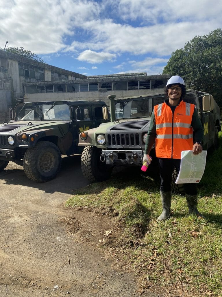 a person in hi-vis standing in front of two vehicles.